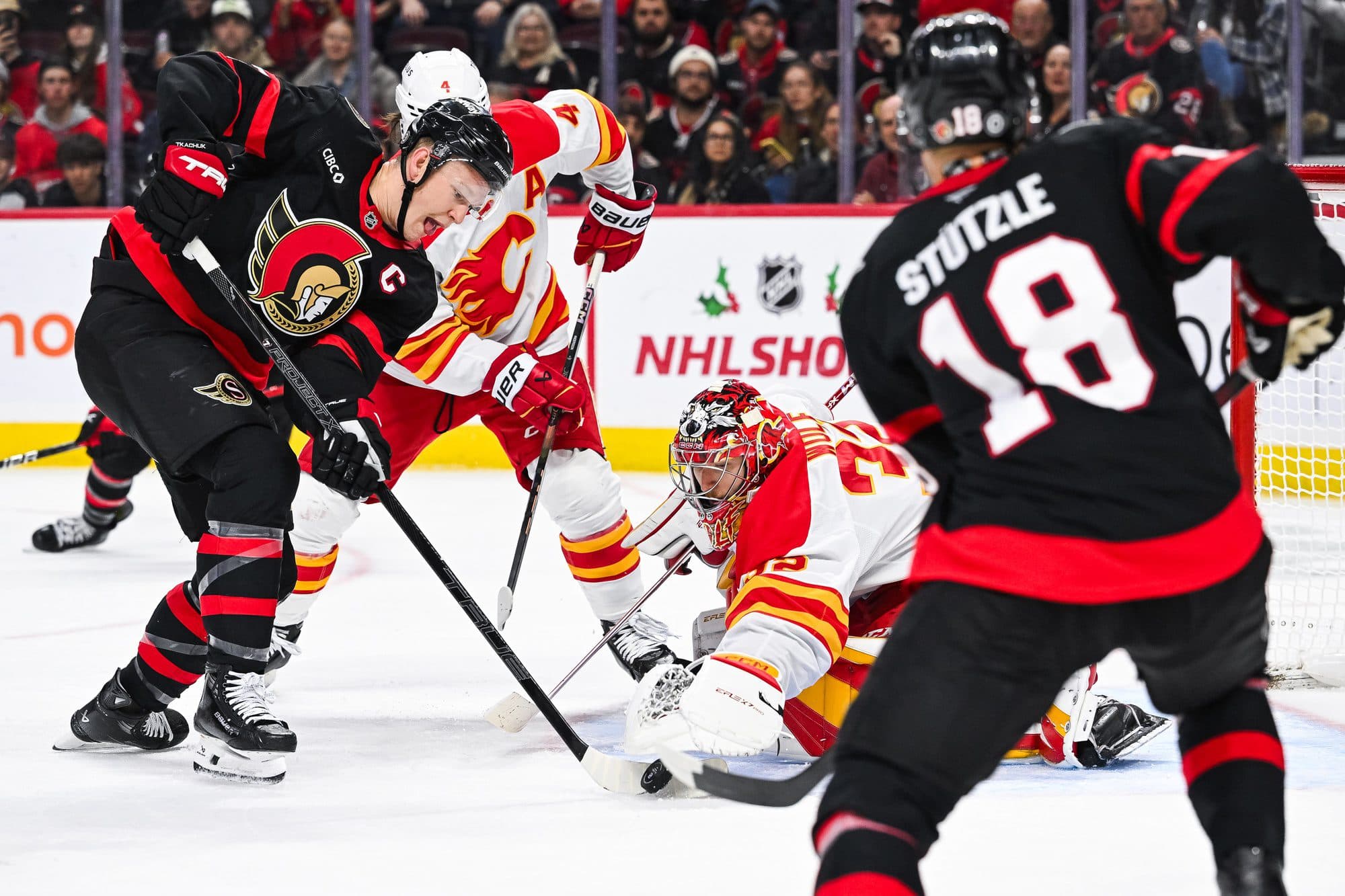 Calgary Flames goalie Dustin Wolf (32) makes a save againt Ottawa Senators left wing Brady Tkachuk (7) during the third period at Canadian Tire Centre