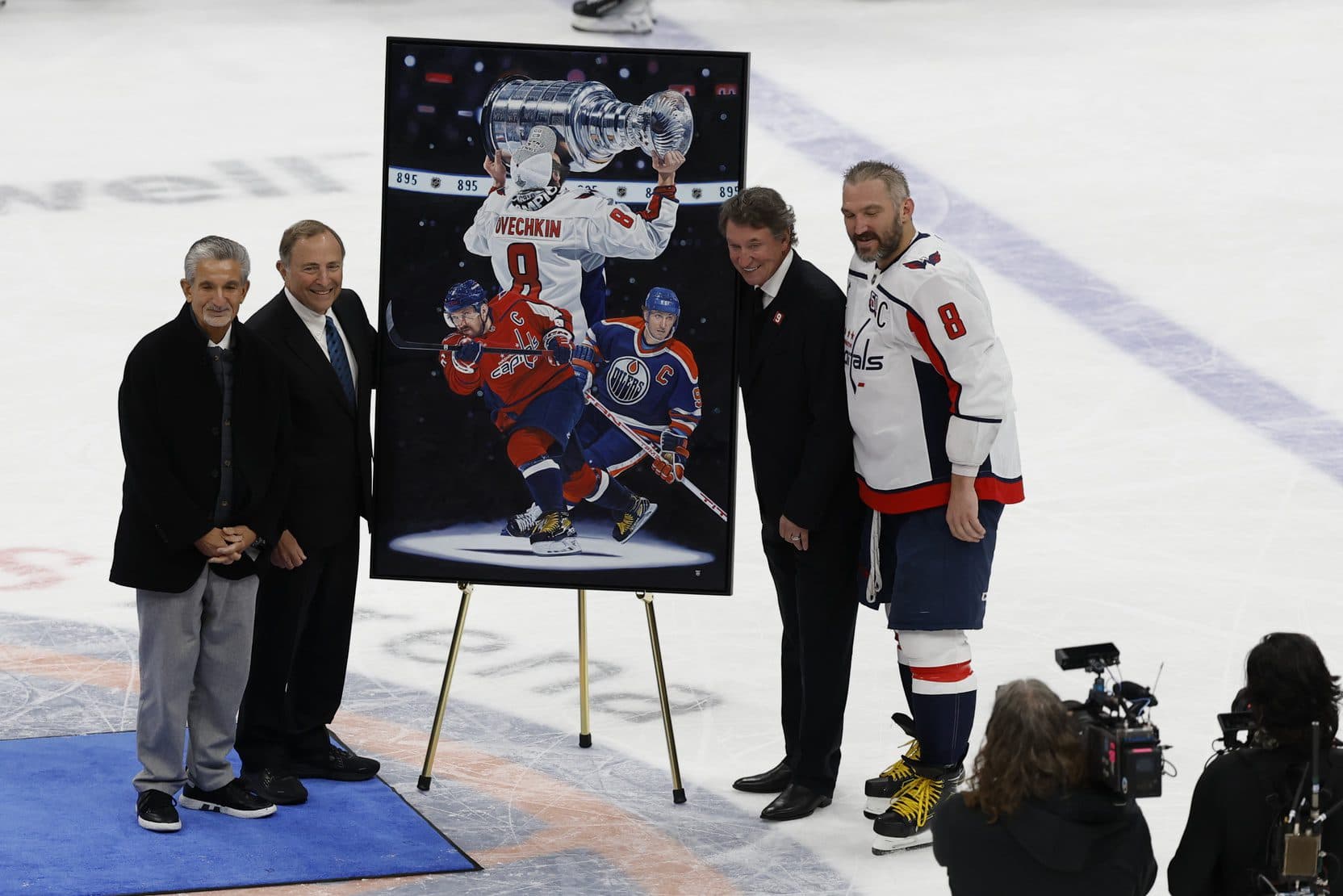 Washington Capitals left wing Alex Ovechkin (8) is honored with a painting by artist Tony Harris by (L-R) Washington Capitals owner Ted Leonis and Commissioner of the NHL Gary Bettman and former Canadian-American ice hockey player Wayne Gretzky after scoring in the during the second period against the New York Islanders at UBS Arena. Ovechkin scored the 895th goal of his career, breaking the NHL all-time career goals record previously held by Wayne Gretzky at UBS Arena.