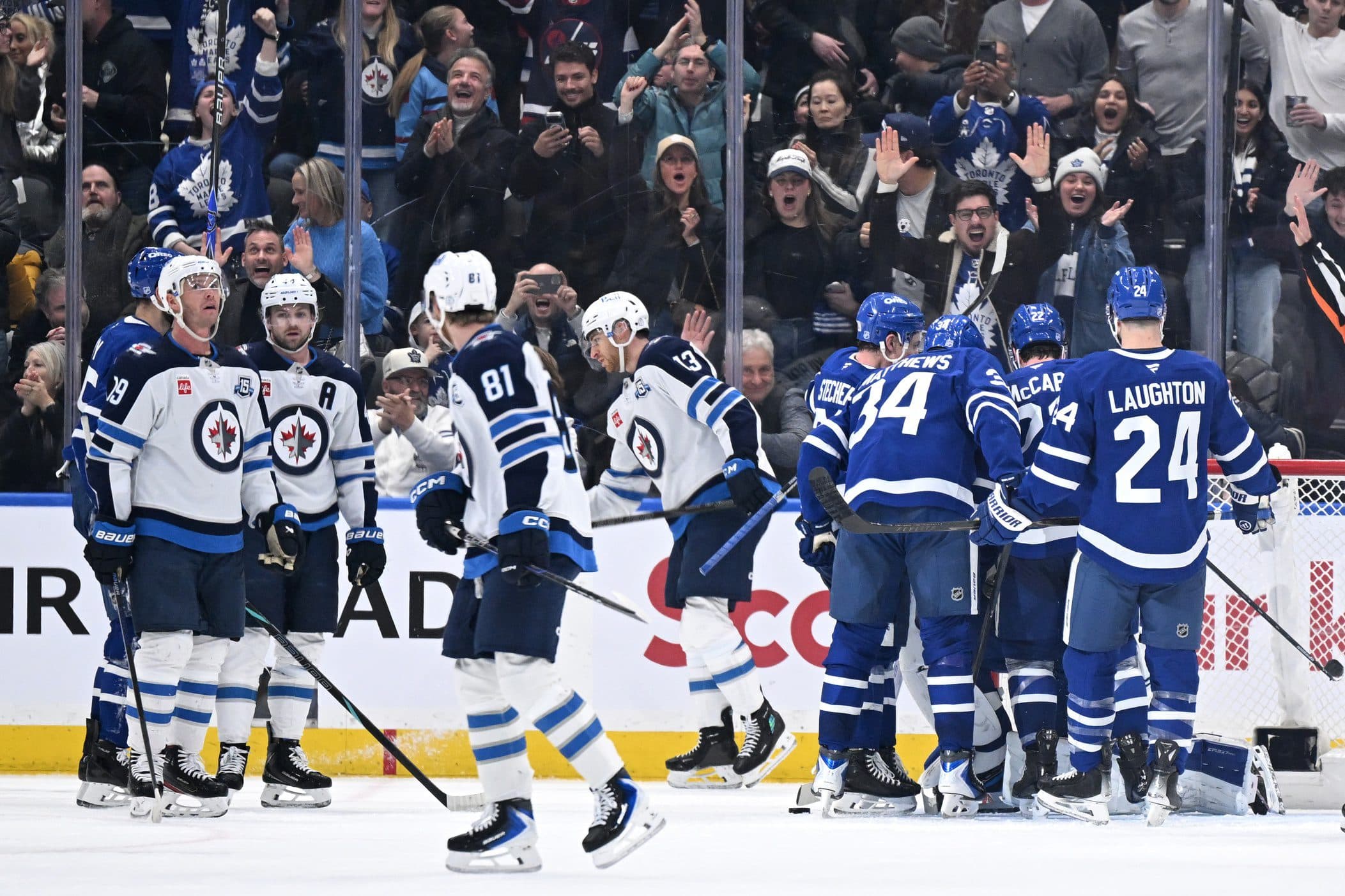 Toronto Maple Leafs players celebrate at the final buzzer with goalie Dennis Hildeby (35, obscured) after defeating the Winnipeg Jets at Scotiabank Arena.
