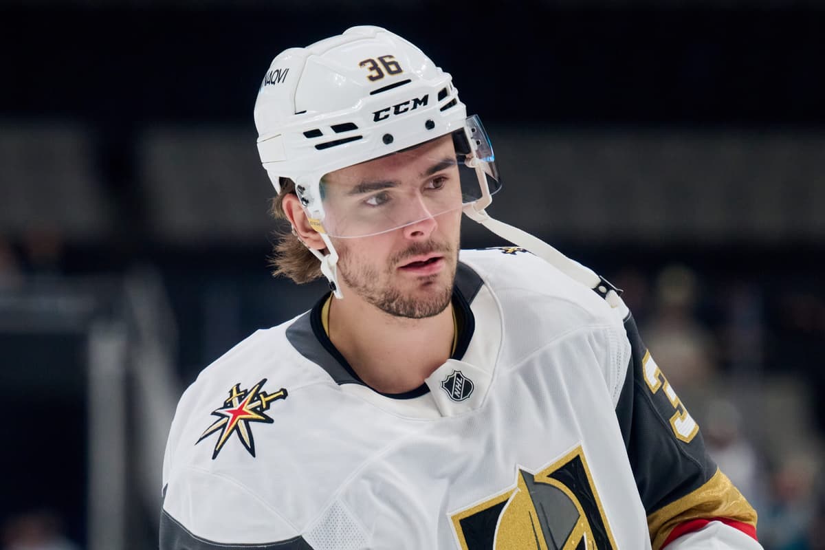 A Vegas Golden Knights player in a white jersey and helmet looks on during warmups, the type of depth player Vegas shuttles between the NHL and Henderson